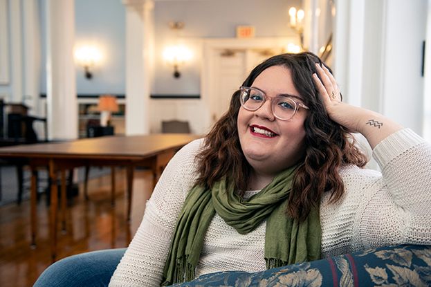 Portrait of Kassandra Colón, Truman Scholar, sitting with hand on her head, smiling.